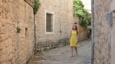 genç kadın elini kolunu sallaya antik bir Avrupa kenti sokaklarında dönüyor