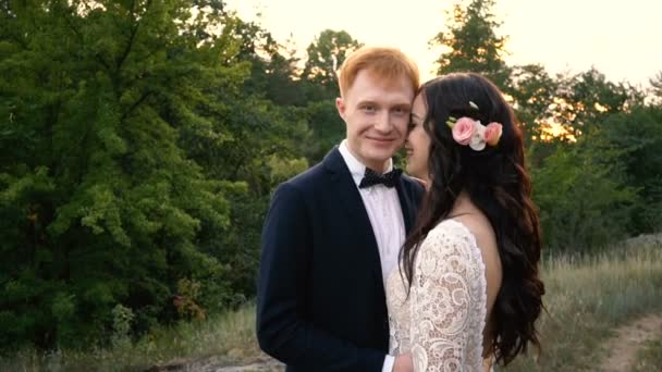 Feliz recém-casados abraçando contra o fundo da natureza, câmera lenta — Vídeo de Stock