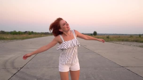 Mujer pelirroja feliz gira, su pelo revoloteando en el viento — Vídeo de stock