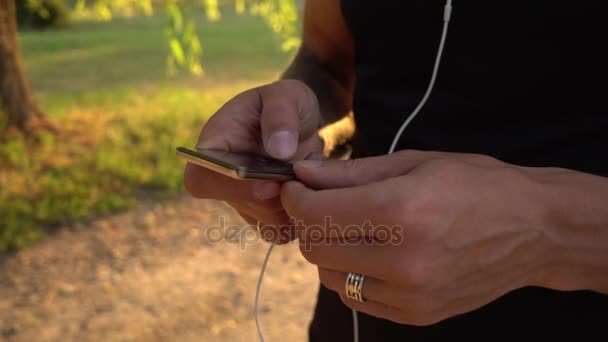 Man browses the playlist on his player before jogging — Stock Video