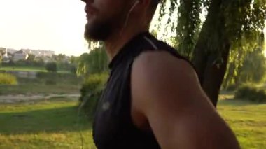 Parkta yolda günbatımında çalışan erkek atlet