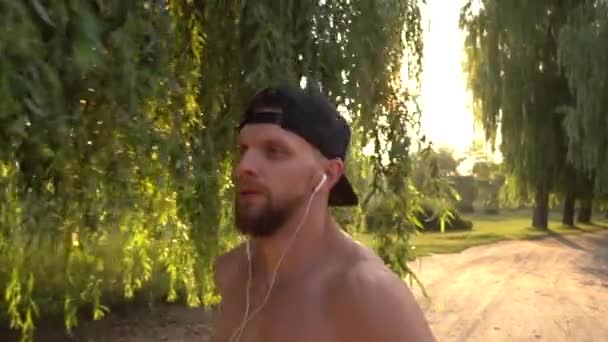 Mannelijke atleet actief op de weg in het park bij zonsondergang — Stockvideo