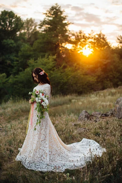 Jeune mariée dehors sur une prairie d'été au coucher du soleil — Photo