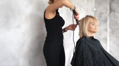 Kuaför saç maşası kullanarak bukleler yapıyor.