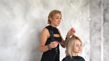 Kuaför saç maşası kullanarak bukleler yapıyor.