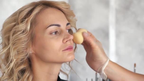 Make-up artist gäller en foundation på framsidan en blond flicka — Stockvideo