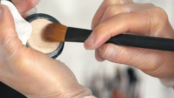 O artista de maquilagem toma uma base tonal de uma escova de maquilagem — Vídeo de Stock