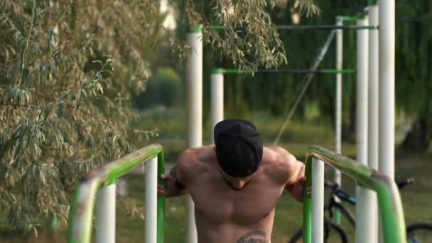 Young man performs a power Exercise On Uneven Bars. — Stock Video