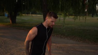 Parkta yolda günbatımında çalışan erkek atlet