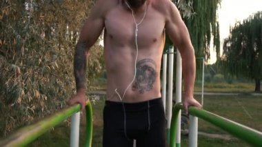Genç adam bir güç egzersiz üzerinde asimetrik paralel gerçekleştirir.