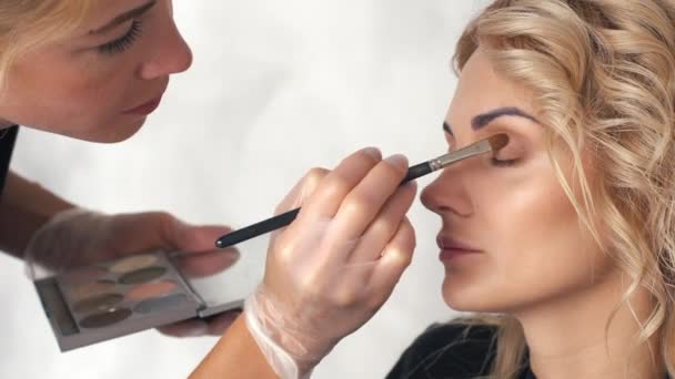 Maquillaje artista pone sombra de ojos en el salón de belleza — Vídeo de stock