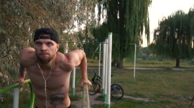 Genç adam bir güç egzersiz üzerinde asimetrik paralel gerçekleştirir.