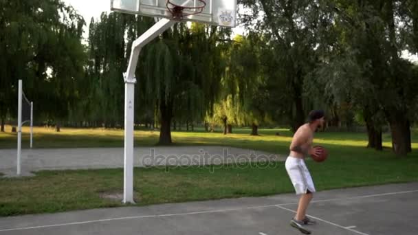 Jovem joga basquete e joga a bola na cesta, bater dunk — Vídeo de Stock