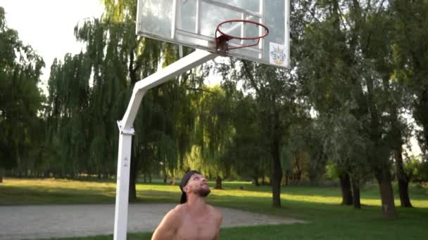 Junger Mann spielt Basketball und wirft den Ball in den Korb — Stockvideo