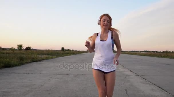 Woman running and listening to music on headphones — Stock Video