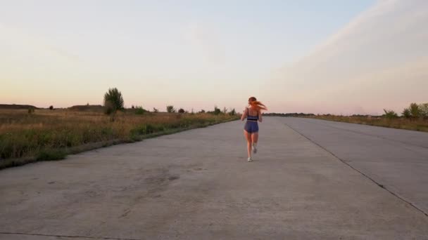 Γυναίκα τρέχει και να ακούτε μουσική με ακουστικά, ΠΙΣΩ ΟΨΗ — Αρχείο Βίντεο
