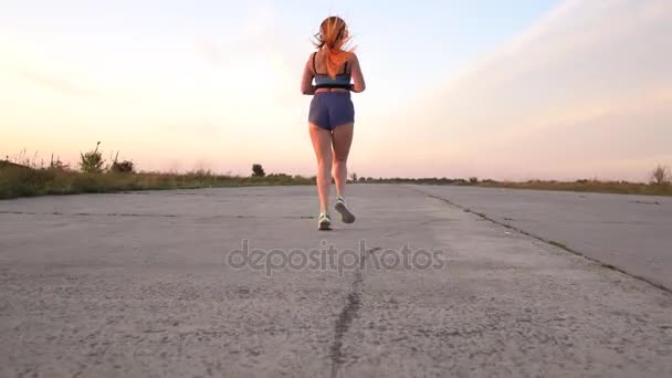 Mujer corriendo y escuchando música en los auriculares, vista trasera — Vídeo de stock