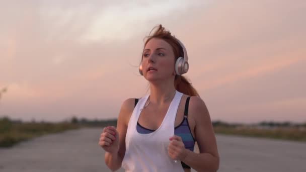 Женщина бегает и слушает музыку на наушниках, замедленная съемка — стоковое видео