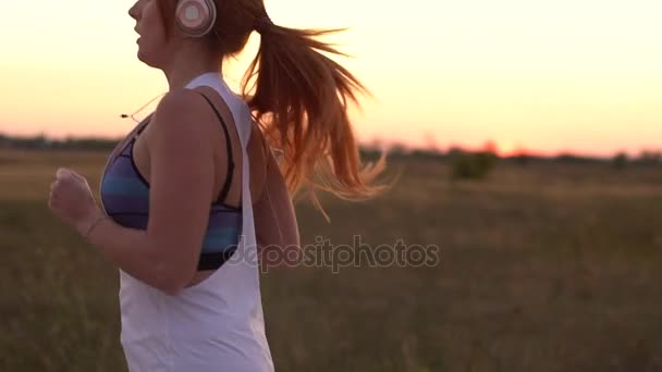 Mujer corriendo y escuchando música en auriculares, cámara lenta — Vídeos de Stock