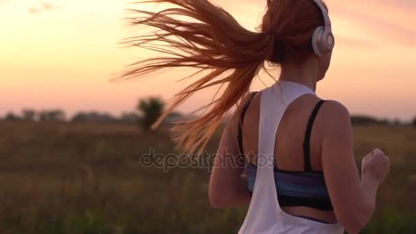 Жінка біжить і слухає музику на навушниках, повільний рух — стокове відео