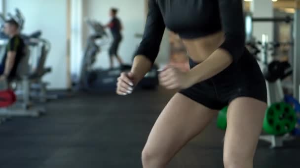 Mujer joven está dando un salto y se abalanza en el gimnasio, cámara lenta — Vídeo de stock