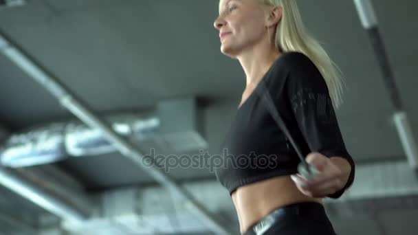 Молодая женщина прыгает через скакалку в спортзале, замедленная съемка — стоковое видео