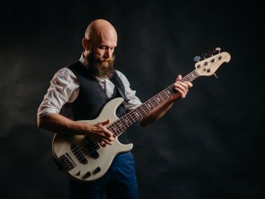 sakallı adam siyah bir arka plan üzerinde gitar çalmak