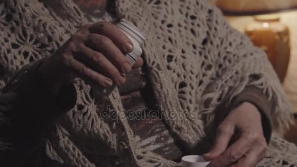 Пожилая женщина вынимает таблетки из бутылки — стоковое видео