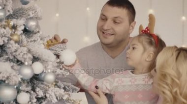 Anne, baba ve küçük kız mutlu genç aileden bir Noel ağacı süslemeleri