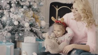 Noel ağacının yanında oturan kızıyla birlikte genç anne