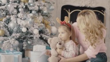Noel ağacının yanında oturan kızıyla birlikte genç anne