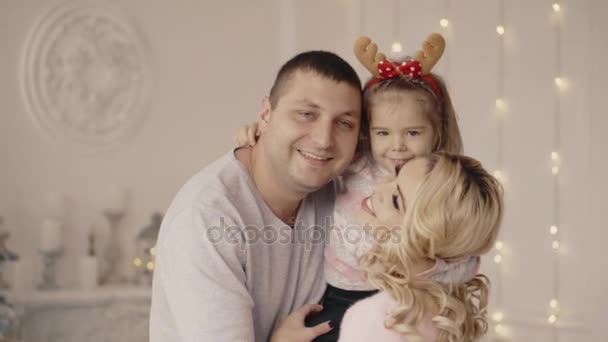 Niña abrazando a mamá y papá cerca del árbol de Navidad — Vídeos de Stock
