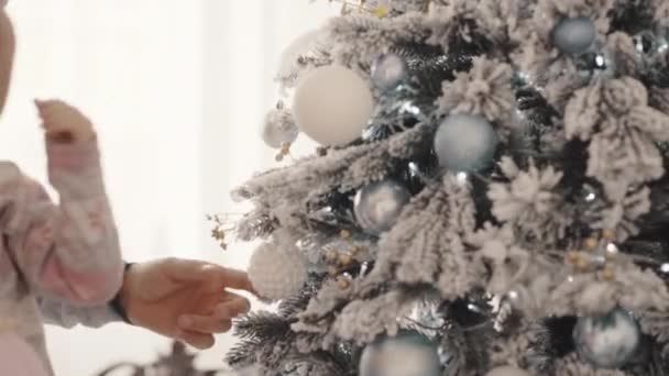 Familia joven y feliz de mamá, papá y niña decorar un árbol de Navidad — Vídeo de stock