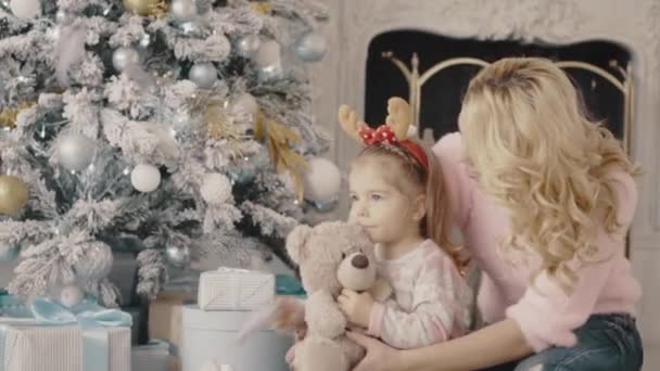 Joven madre con su hija sentada cerca del árbol de Navidad — Vídeos de Stock