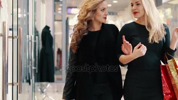 Dos mujeres eligen ropa en la tienda cerca de la tienda — Vídeo de stock