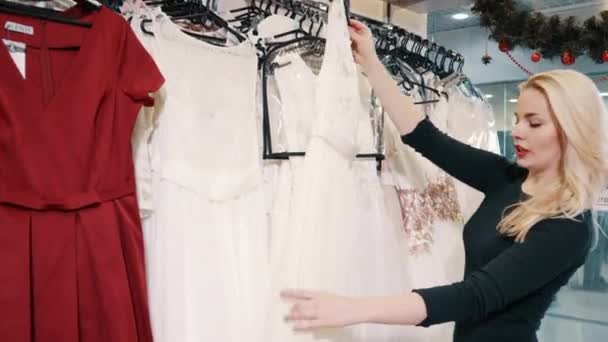 Jeune femme choisit des vêtements dans le magasin — Video