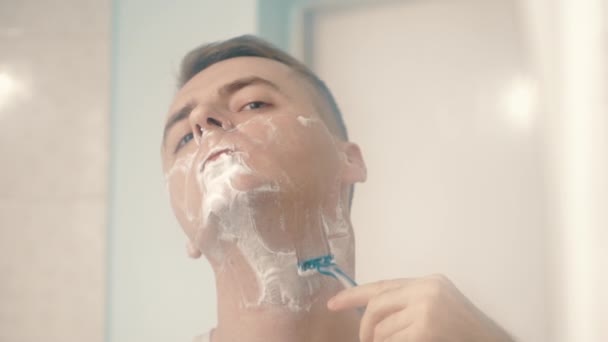 Молодой человек сбрил лицо в ванной — стоковое видео