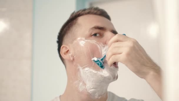 Молодой человек сбрил лицо в ванной — стоковое видео