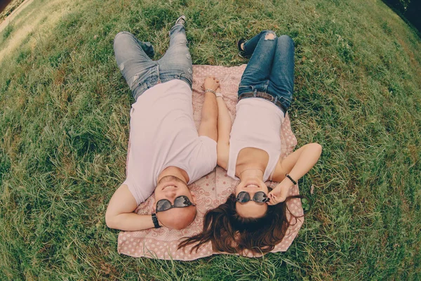 Para młodych kochanków leżeć na trawie i uśmiech — Zdjęcie stockowe