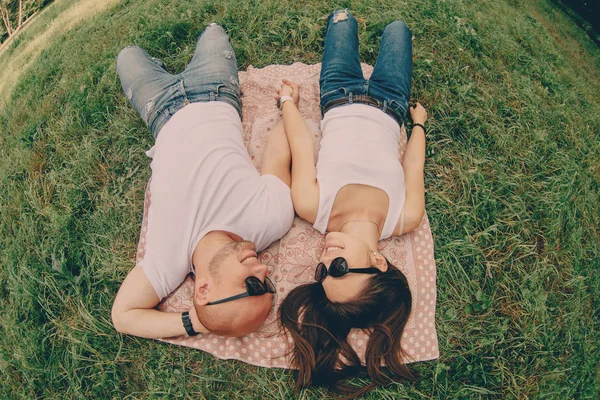 Paar jonge liefhebbers liggen op het gras en de glimlach — Stockfoto