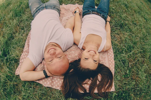 Pareja de jóvenes amantes yacen en la hierba y sonríen —  Fotos de Stock