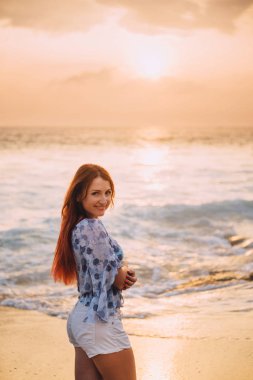 okyanus tarafından ayakta ve gülümseyen genç Kızıl saçlı kadın