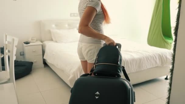 Joven mujer feliz entra con una maleta en su habitación de hotel — Vídeos de Stock