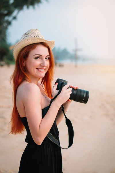 Młoda kobieta fotograf stoi na plaży z aparatem w dłoni, zbliżenie — Zdjęcie stockowe