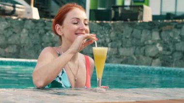 genç kadın bir kokteyl havuzda içecekler.