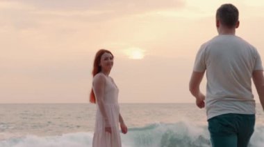 Genç çift günbatımı okyanus kıyısında, arka yüzüne hayran