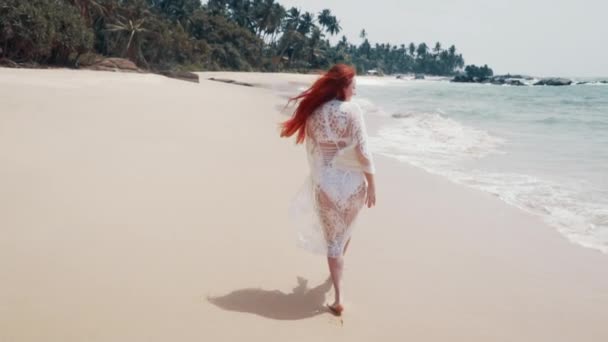 Jonge vrouw loopt langs het strand van de Oceaan op een zonnige dag — Stockvideo