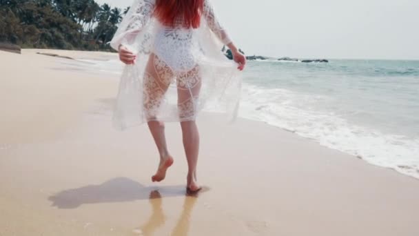 Jovem mulher corre ao longo da praia do oceano em um dia ensolarado — Vídeo de Stock