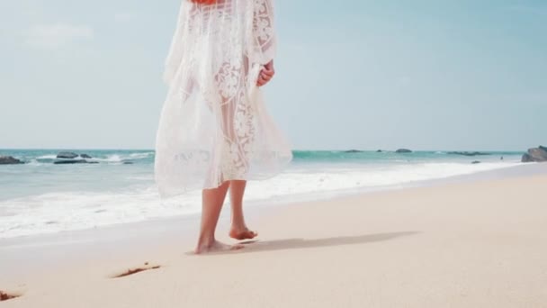 Pies de una mujer joven caminando a lo largo de una playa del océano en un día soleado — Vídeos de Stock