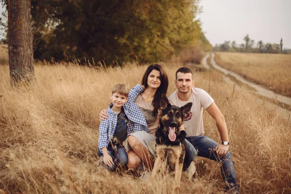 Mamá papá e hijo sentado en la hierba con su perro —  Fotos de Stock